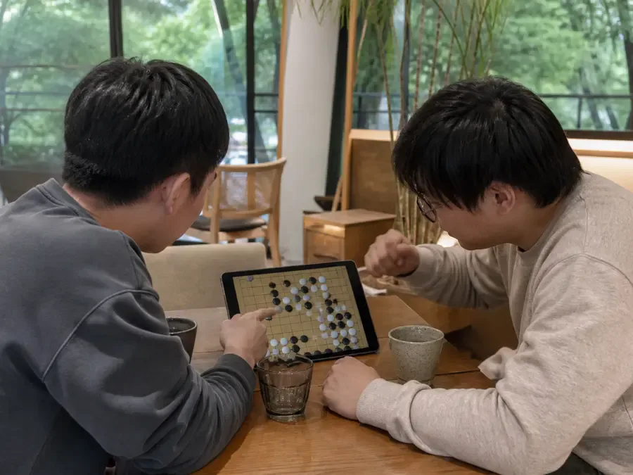 Two people playing Go together on one tablet